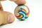 Index or pointing finger touching colorful rubber marble ball is