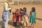 India, Hampi, 02 February 2018. A bald and cheerful European man gives gifts to Indian children. Joyful children are pulling their