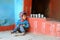 Indian barefoot boy in worn out poor clothes sitting on stone floor in outdoor traditional asian kitchen on 10.22.2017 in Dwarahat