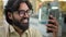 Indian bearded businessman in glasses talk video call on smartphone Arabian guy man executive entrepreneur business