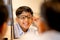 Indian boy touch glasses leg and smile to mirror also stay near his father in optical shop