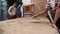 Indian boys watch their friend realigning sand with a trowel.