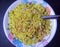 Indian breakfast yellow poha dish garnished with chopped onions and namkeen sev