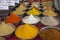 Indian bright colored spice powders in metal cups on the counter