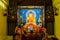 Indian Buddhist monk and people standing and praying on bare foot in front of large statue of lord Buddha inside Mahabodhi Temple.