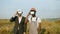 Indian businessman in suit and african american engineer in uniform using VR goggles for work on farm with wind turbines