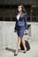 Indian businesswoman in formal clothing walking with wheeled bag