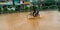 indian children riding bicycle during raining season on road