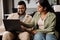 Indian colleagues using laptop while sitting on couch in office