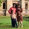 Indian couple posing for maternity baby shoot with their 5 year old kid. The couple is posing in a lawn with green grass and the