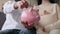 Indian Couple Putting Coins In Piggy Bank At Home