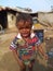 An Indian crying child in front of a hut.