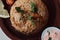 Indian dish with rice, sauce, lemon, tomato and coriander leaf on wooden tray.