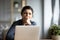 Indian employee sitting at desk yawning feels unmotivated and tired