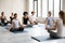 Indian ethnicity woman with like-minded people meditating indoors