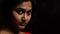 An indian female staring at the camera with thoughtful expression in black background with selective focus on rear eye