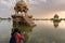 Indian female traveller, woman photographer taking picture of Chhatris and shrines with reflection of them on the water of Gadisar