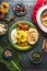 Indian food dish with paneer cheese , curries, rice, naan bread, samosas on dark rustic background