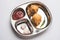 Indian food snack Aloo Bonda or potato pakoda or pakora served in a stainless steel plate with tomato ketchup