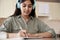 Indian girl wearing headphones writing homework listening audio course at home.