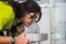 An indian lady in green dress drinking water from a steel water fountain on a sink by pressing button at airport.