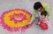 Indian male with his son creating rangoli using candles, marigold and pink rose petals