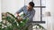 Indian man cleaning houseplant`s leaves at home