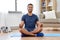 Indian man meditating in lotus pose at home