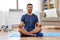 Indian man meditating in lotus pose at home