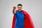 Indian man in superhero cape flying over grey