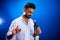 Indian man in white shirt with beard singing in recording studio on blue background