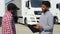 Indian manager and african trucker shaking hands by truck. Two people shaking hands on truck parking