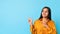 Indian millennial woman in casual excitedly pointing aside, blue background