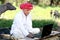 Indian old farmer smiles using laptop and internet