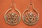 Indian ornamental style brass earrings on orange background