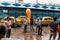 Indian people waiting in front of Indian Museum for selling long form orange balloon with yellow taxis on the road in background.