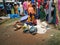 Indian Poor Mother and Child selling Coconut, Lime, Banana and Flowers or Puja Items in a Roadside near the Temple