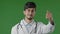 Indian professional male doctor arabian man doctor intern in white medical uniform stands in green studio make welcome