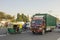 Indian red truck and auto rickshaw in street city traffic on a background of green trees and a white