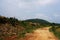 A Indian rural village soily road landscape with blue sky and white clouds background passing beside a small hill or hillock.