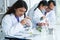 Indian scientist woman student using microscope do an experiment at biology class in school laboratory while teacher teaching