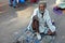 Indian senior physically challenged man seeking help / begging sitting on a busy road