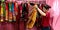 an indian shopkeeper girl holded traditional women outfits at garment store