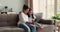 Indian sisters grownup and kid sit on couch using phone