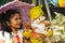 Indian small girl with cartoon statue smiling while holding pink umbrella inside garden, Pune