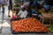 An Indian street vendor selling tomatoes at his roadside stall in a busy vegetable market