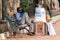 An Indian street vendor sitting on a bench and selling snacks at his stall at the