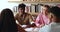 Indian student guy sit at desk talking with multinational schoolmates