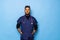 Indian surgeon standing setting his gloves to start the surgery, wearing a mask and a blue uniform, isolated on a blue background