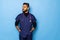 Indian surgeon standing setting his gloves to start the surgery, wearing a mask and a blue uniform, isolated on a blue background